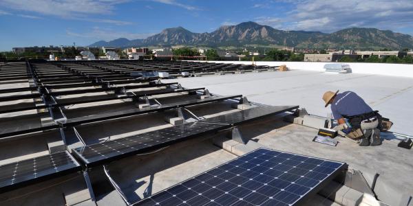 a technician installs solar panels on the roof of the building which houses the University of babyֱapp Center for Innovation and Creativity in Boulder. 